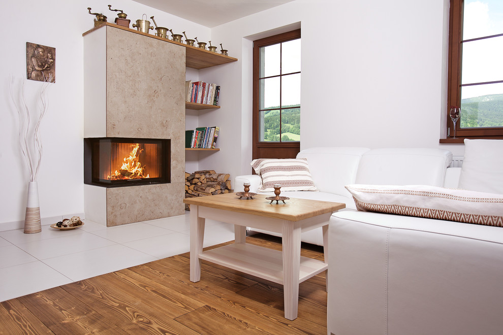 Imagen de sala de estar abierta actual de tamaño medio sin televisor con paredes blancas, estufa de leña, marco de chimenea de yeso y suelo marrón