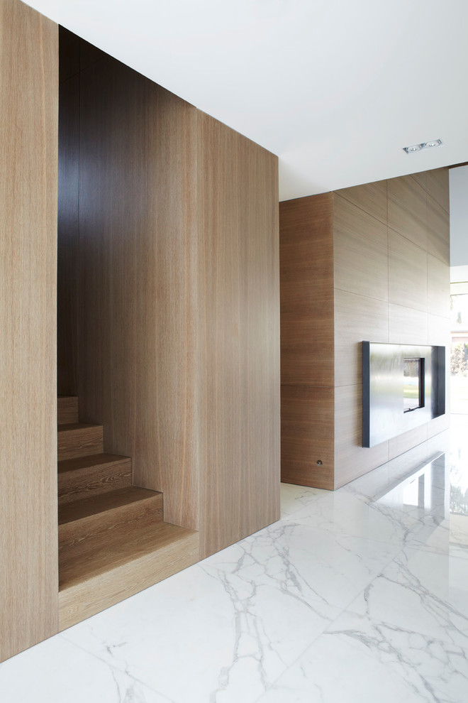 На фото: большая открытая гостиная комната в современном стиле с мраморным полом, двусторонним камином, коричневыми стенами и фасадом камина из металла с
