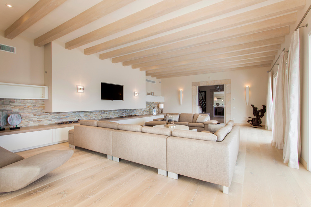 Imagen de sala de estar cerrada actual extra grande sin chimenea con paredes beige, suelo de madera clara y televisor colgado en la pared