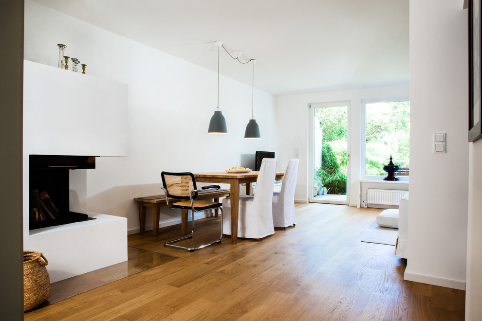 Example of a mid-sized trendy open concept medium tone wood floor family room design in Munich with white walls, a corner fireplace, a plaster fireplace and a tv stand