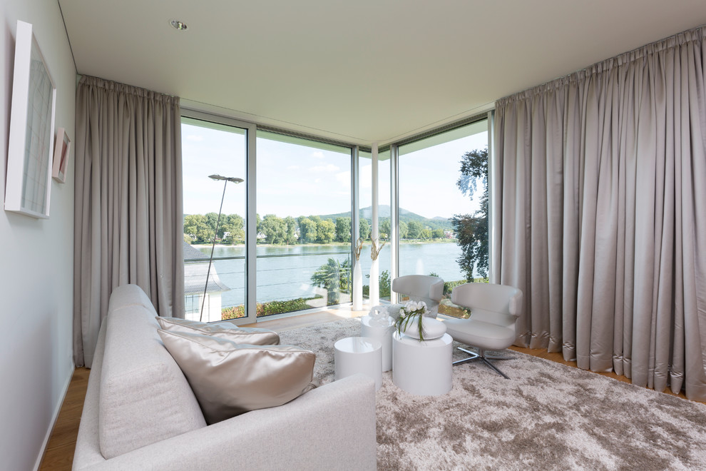 Mittelgroßes, Fernseherloses, Abgetrenntes Modernes Wohnzimmer ohne Kamin mit weißer Wandfarbe, braunem Holzboden und braunem Boden in Köln