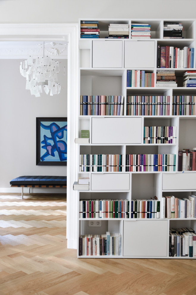 Foto di un grande soggiorno minimal aperto con libreria, pareti grigie, parquet chiaro, nessun camino e TV a parete