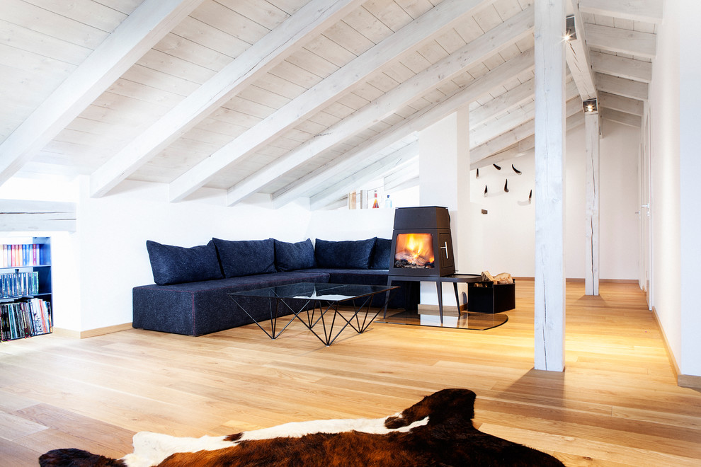 Skandinavisk inredning av ett stort separat vardagsrum, med vita väggar, ljust trägolv, en öppen vedspis, ett finrum, en spiselkrans i metall, en dold TV och brunt golv