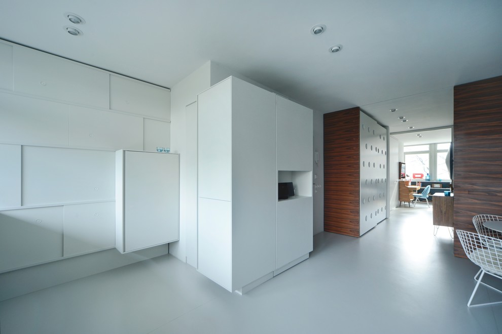 Imagen de salón abierto contemporáneo de tamaño medio sin chimenea con paredes blancas, suelo de linóleo, suelo blanco y televisor colgado en la pared