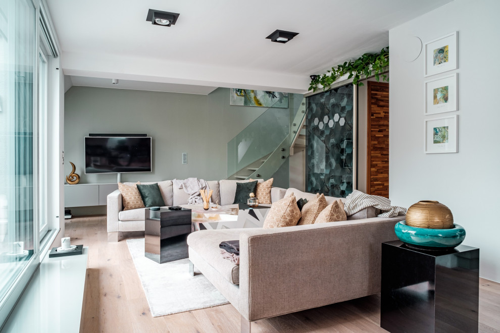 Ejemplo de sala de estar tipo loft contemporánea grande sin chimenea con paredes blancas, suelo de madera en tonos medios, televisor colgado en la pared, suelo beige y papel pintado