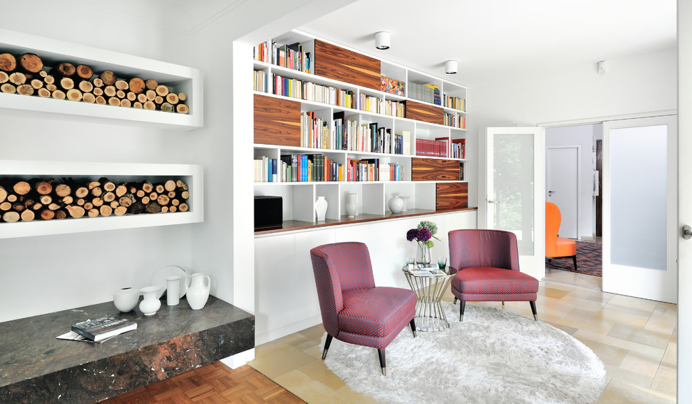 Modelo de sala de estar con biblioteca abierta vintage grande sin televisor con paredes blancas, suelo beige, chimenea de doble cara y marco de chimenea de yeso