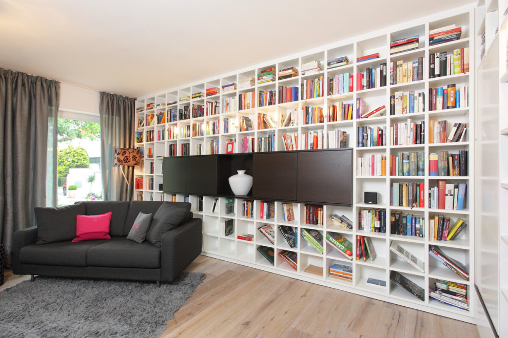 Ejemplo de sala de estar con biblioteca contemporánea con suelo de madera clara y suelo beige