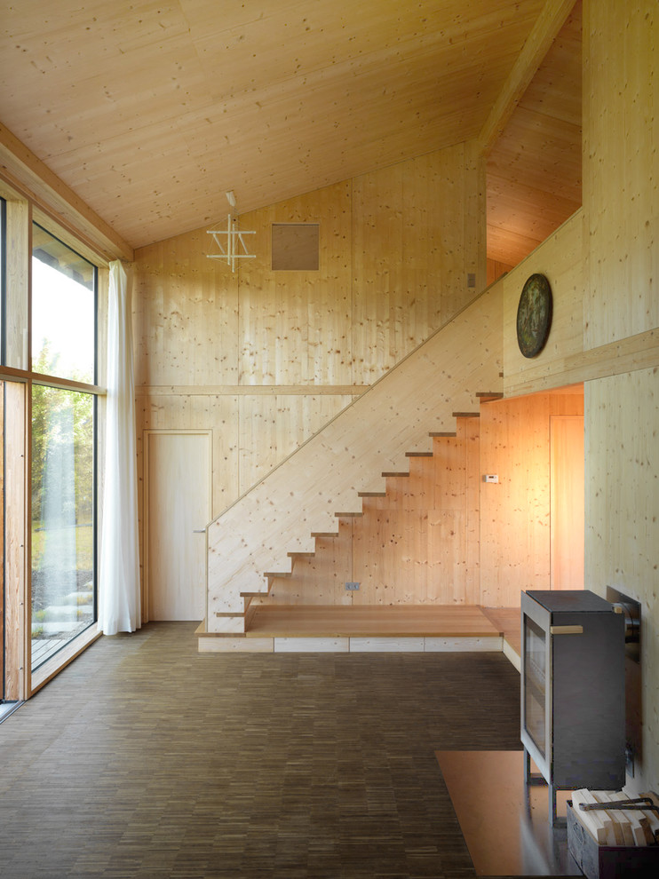 Ejemplo de salón cerrado rural grande con estufa de leña, marco de chimenea de metal, suelo de madera oscura y paredes marrones