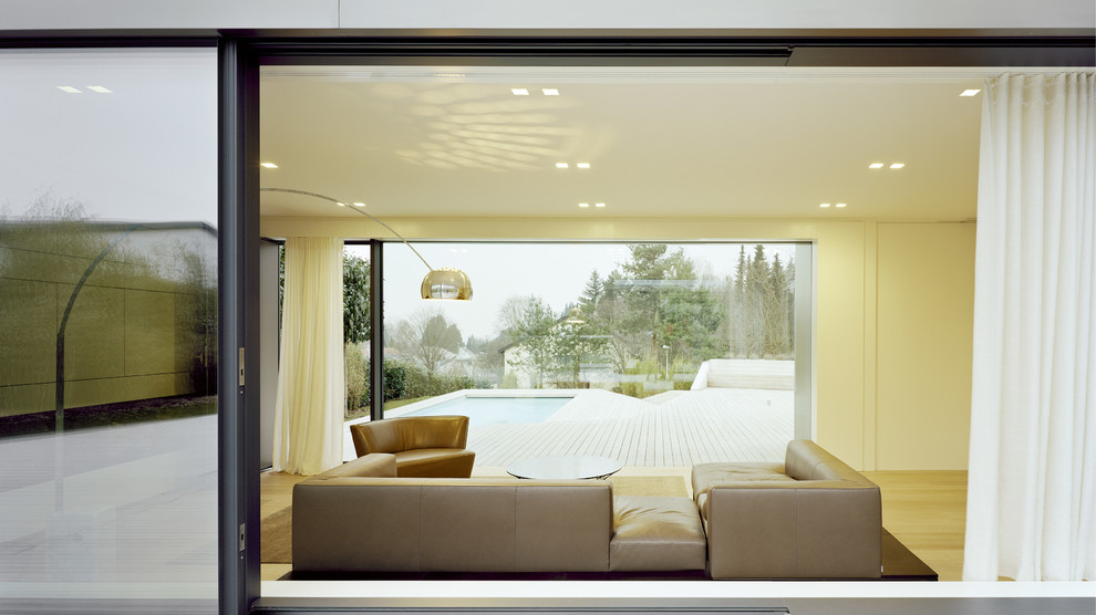 Exempel på ett stort modernt allrum med öppen planlösning, med vita väggar och ljust trägolv