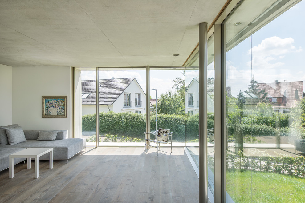 Großes, Abgetrenntes Modernes Wohnzimmer mit weißer Wandfarbe und braunem Holzboden in Stuttgart