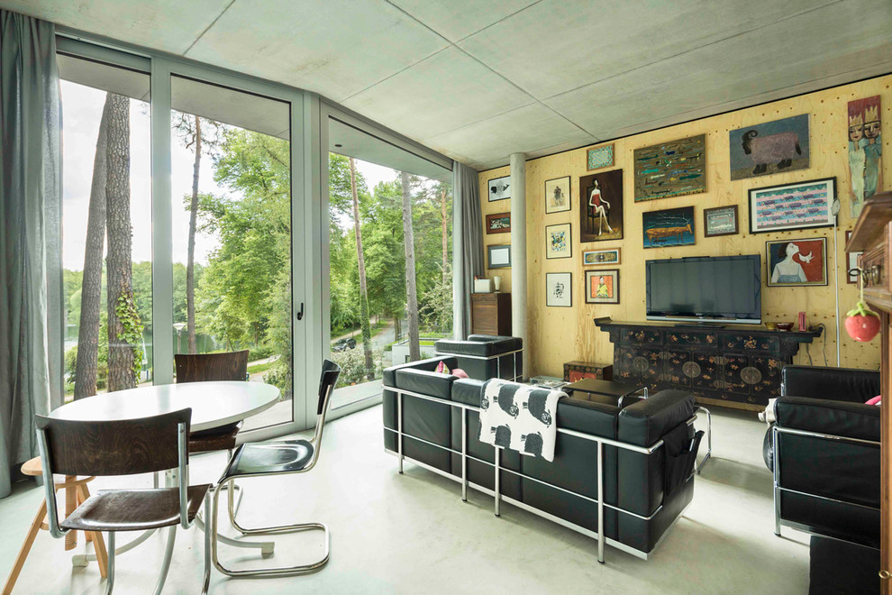 На фото: открытая гостиная комната в современном стиле с бетонным полом и отдельно стоящим телевизором с