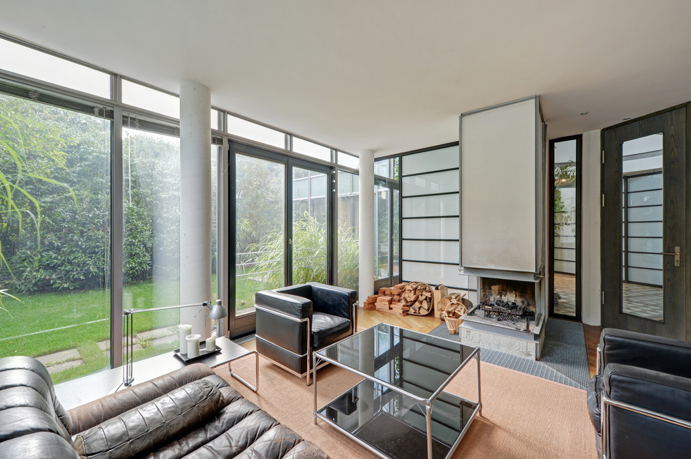 Immagine di un grande soggiorno design chiuso con sala formale, pavimento in legno massello medio, camino bifacciale e nessuna TV