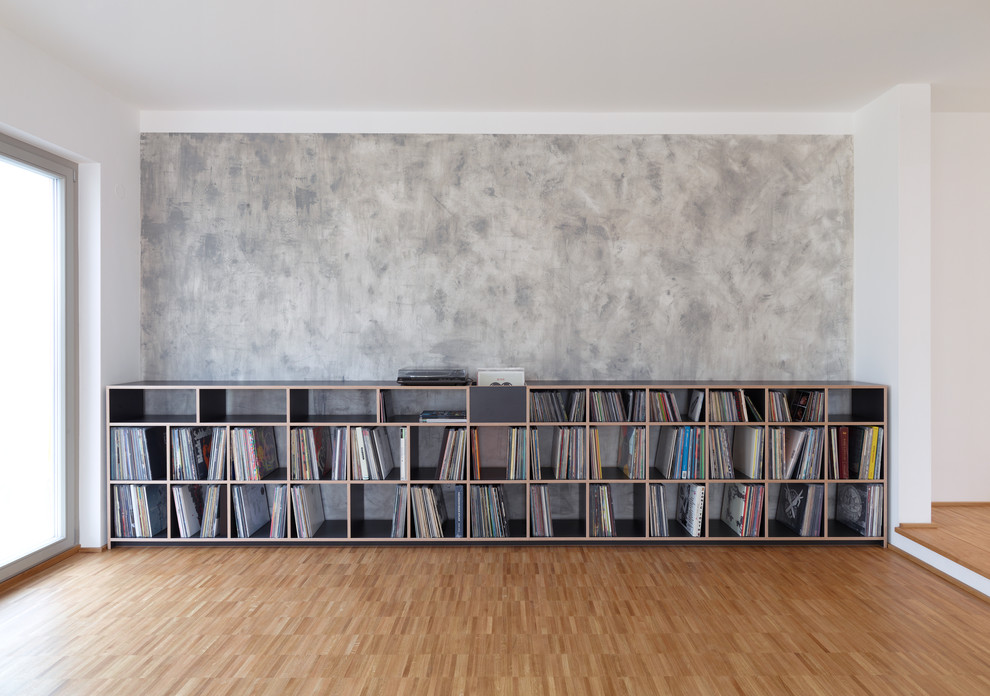Diseño de salón abierto contemporáneo grande con paredes grises y suelo de madera clara