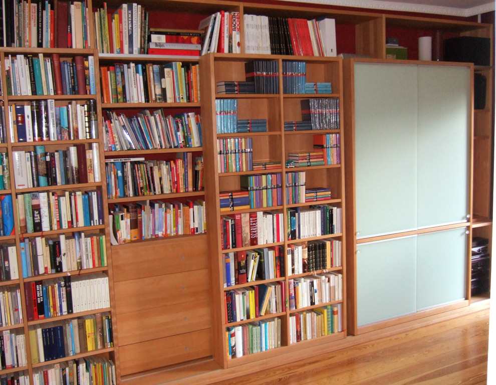 Modelo de biblioteca en casa cerrada contemporánea de tamaño medio con paredes blancas, suelo de madera clara y suelo marrón