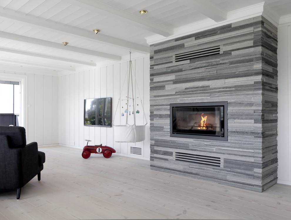 Cette image montre un salon design avec un mur blanc, parquet clair, une cheminée standard, un manteau de cheminée en pierre, un téléviseur fixé au mur et un mur en pierre.