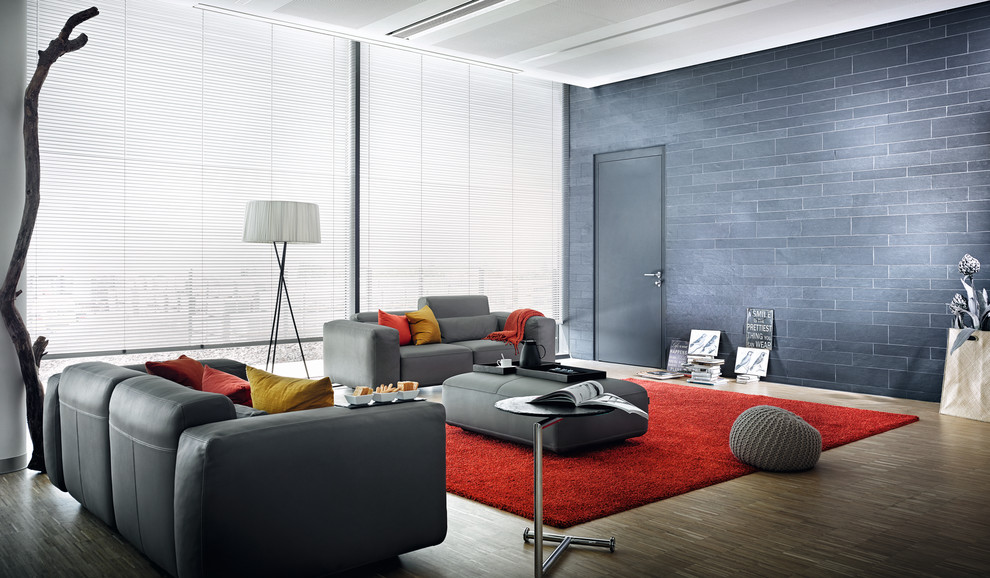 Imagen de salón abierto actual con paredes grises y suelo de madera oscura