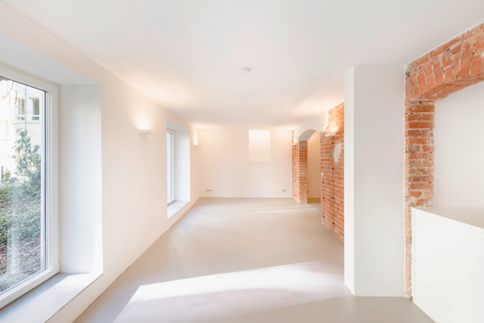 Modern inredning av ett stort allrum med öppen planlösning, med vita väggar och grått golv