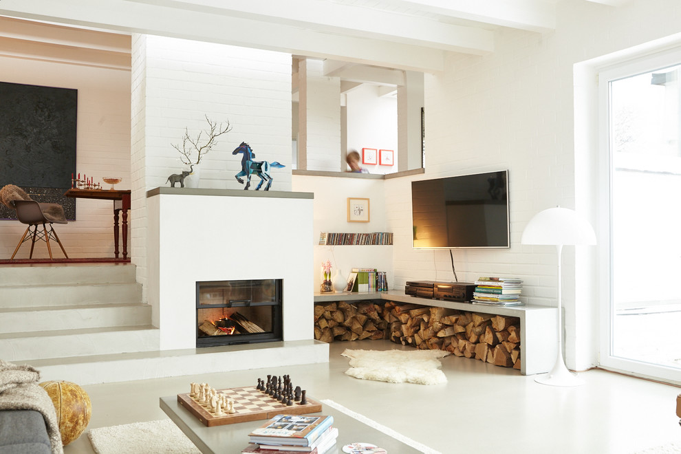 Imagen de sala de estar abierta contemporánea de tamaño medio con paredes blancas, todas las chimeneas, televisor colgado en la pared y marco de chimenea de yeso