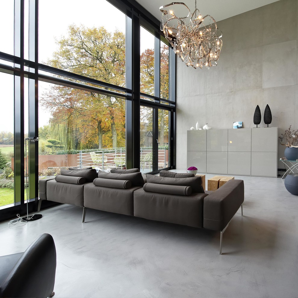 Diseño de salón abierto moderno grande con paredes grises y suelo de cemento