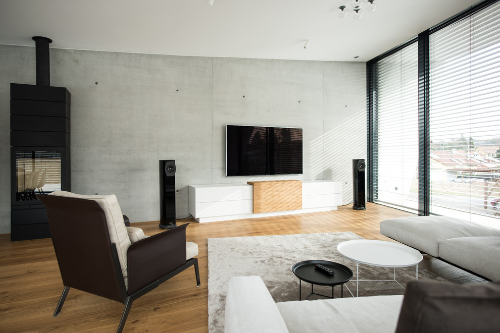 Cette image montre une salle de séjour urbaine de taille moyenne et fermée avec un mur gris, un sol en bois brun, une cheminée standard, un téléviseur fixé au mur et un sol marron.