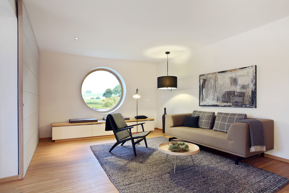 Стильный дизайн: изолированная гостиная комната среднего размера в скандинавском стиле с белыми стенами и полом из бамбука - последний тренд