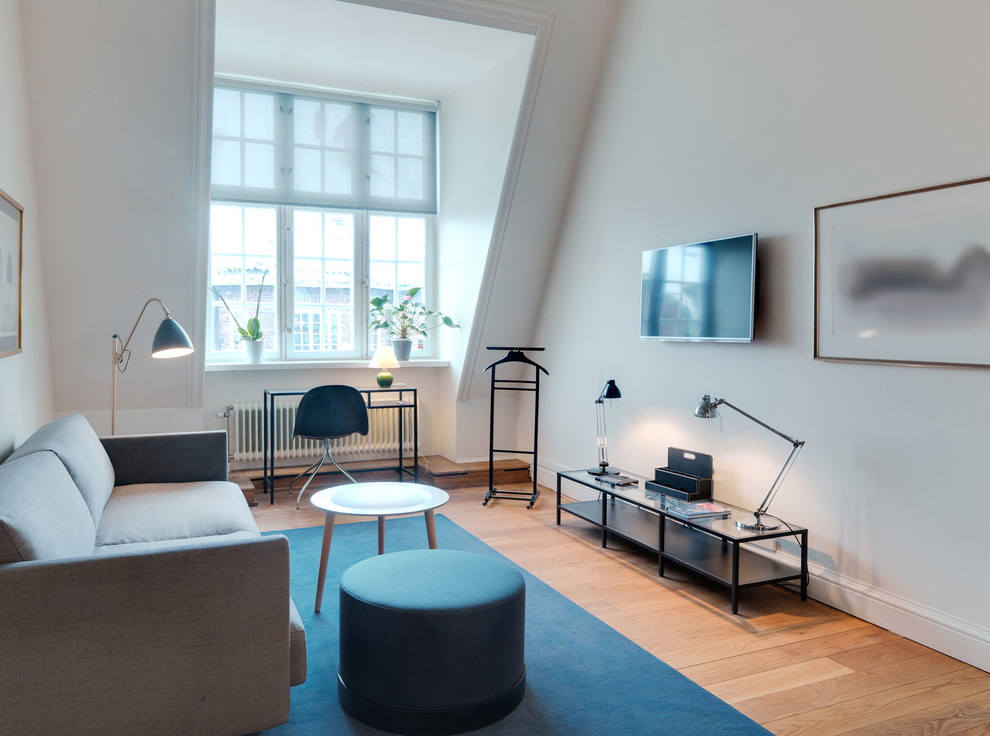 Foto på ett mellanstort skandinaviskt separat vardagsrum, med vita väggar, mellanmörkt trägolv och en väggmonterad TV