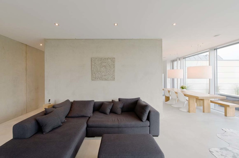 На фото: открытая гостиная комната среднего размера в современном стиле с бетонным полом и серыми стенами