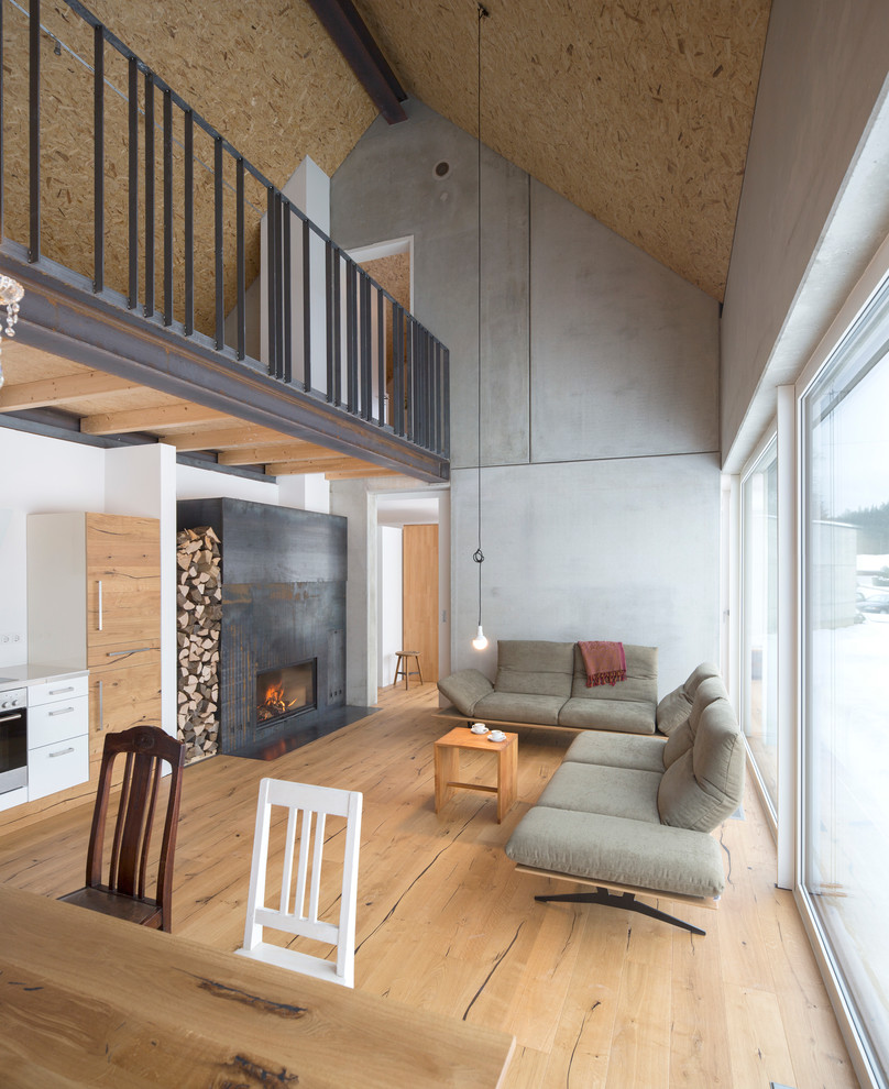 Offenes, Mittelgroßes Industrial Wohnzimmer mit grauer Wandfarbe, hellem Holzboden, Kaminumrandung aus Metall und braunem Boden in Sonstige