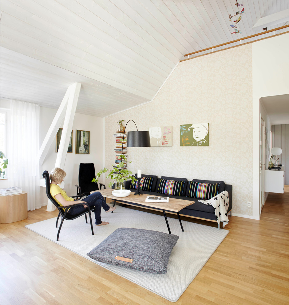 Cette photo montre une grande salle de séjour scandinave avec un mur beige, parquet clair, aucune cheminée, aucun téléviseur et canapé noir.