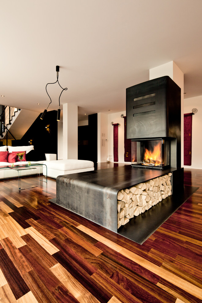 Großes Industrial Wohnzimmer mit braunem Holzboden, Eckkamin und Kaminumrandung aus Metall in Sonstige