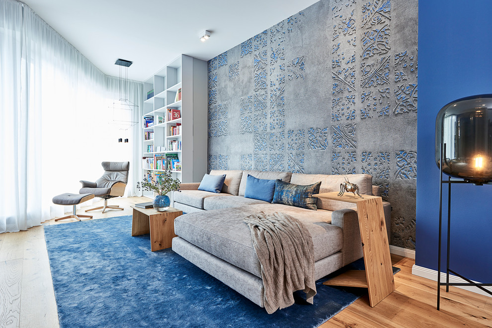 Esempio di un grande soggiorno design chiuso con libreria, pareti blu, pavimento in legno massello medio, TV a parete, pavimento marrone e nessun camino