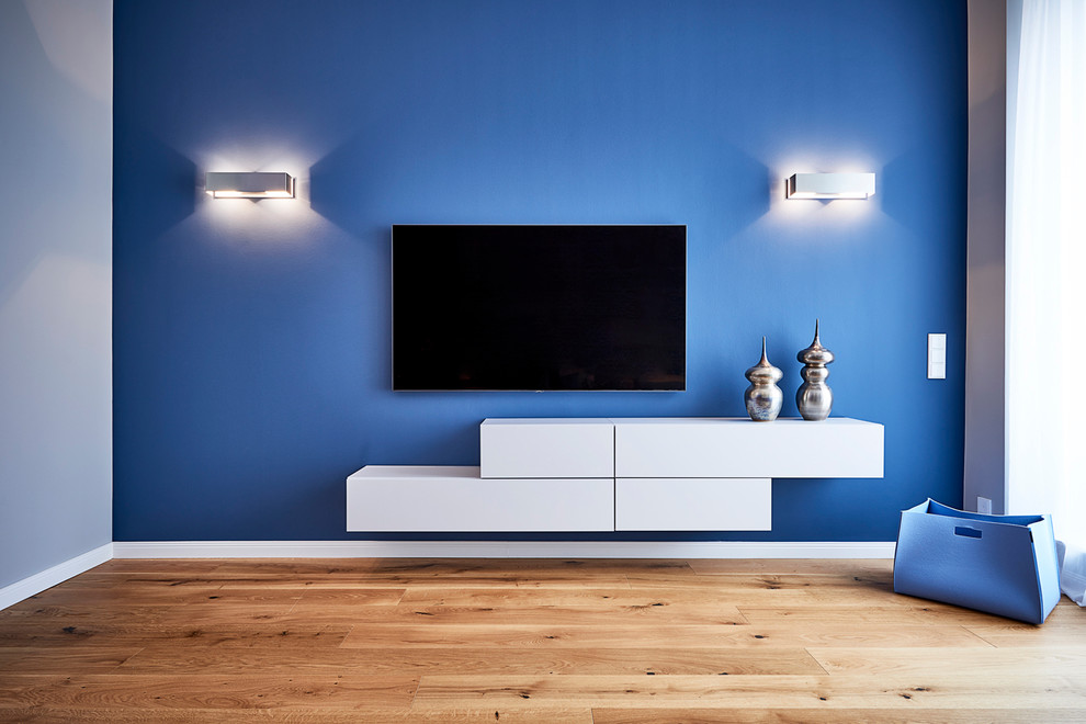 Exemple d'une grande salle de séjour tendance fermée avec un mur bleu, un sol en bois brun, un téléviseur fixé au mur et un sol marron.