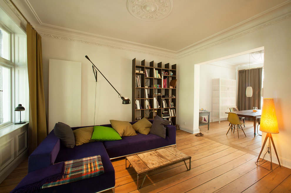 Imagen de sala de estar abierta bohemia de tamaño medio sin chimenea con paredes blancas y suelo de madera en tonos medios