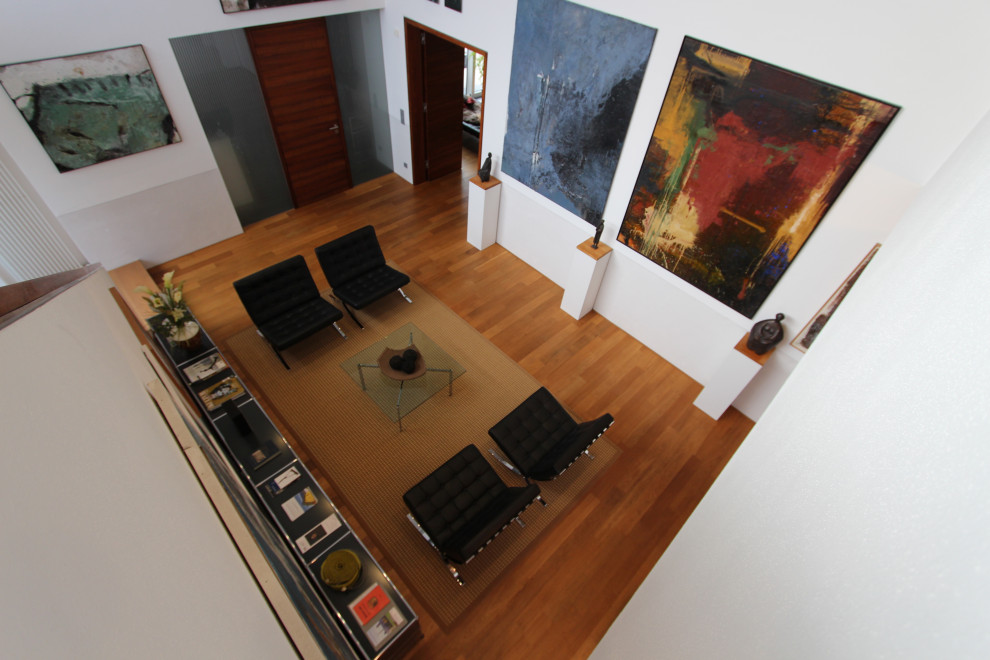 Diseño de salón para visitas abierto contemporáneo pequeño sin chimenea y televisor con paredes blancas, suelo de madera en tonos medios y suelo marrón