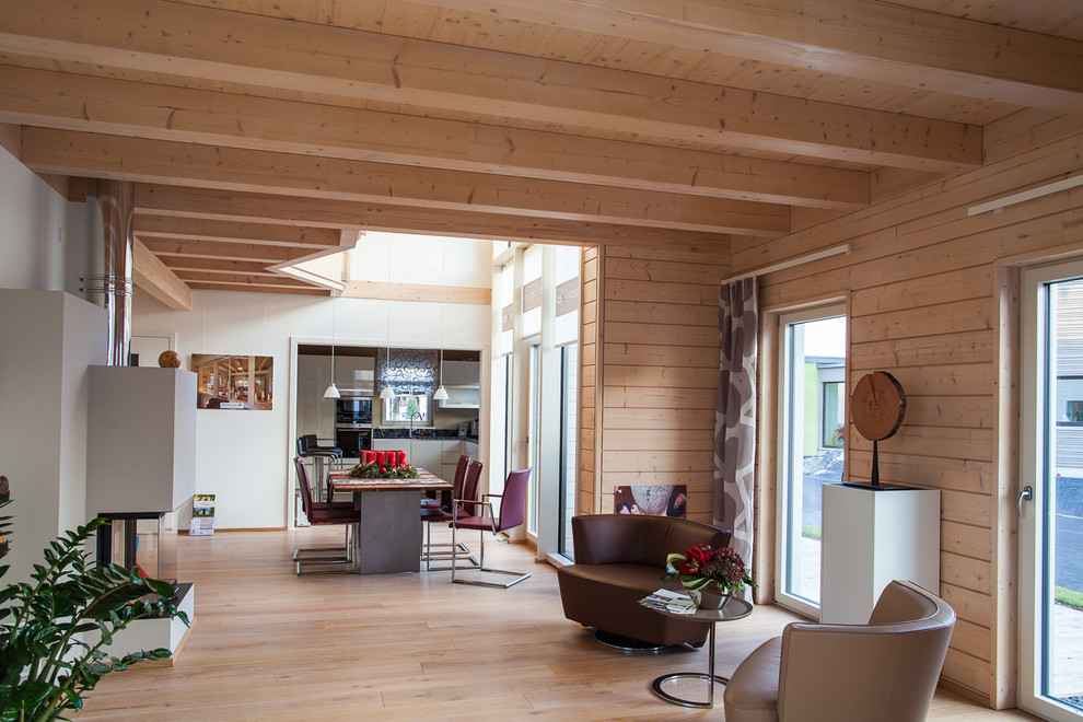 Imagen de salón abierto actual de tamaño medio sin televisor con paredes blancas, suelo de madera clara, chimenea lineal y marco de chimenea de yeso