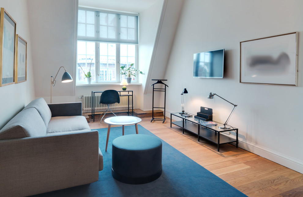 Foto di un piccolo soggiorno moderno chiuso con libreria, pareti bianche, pavimento in legno massello medio, TV a parete e pavimento marrone