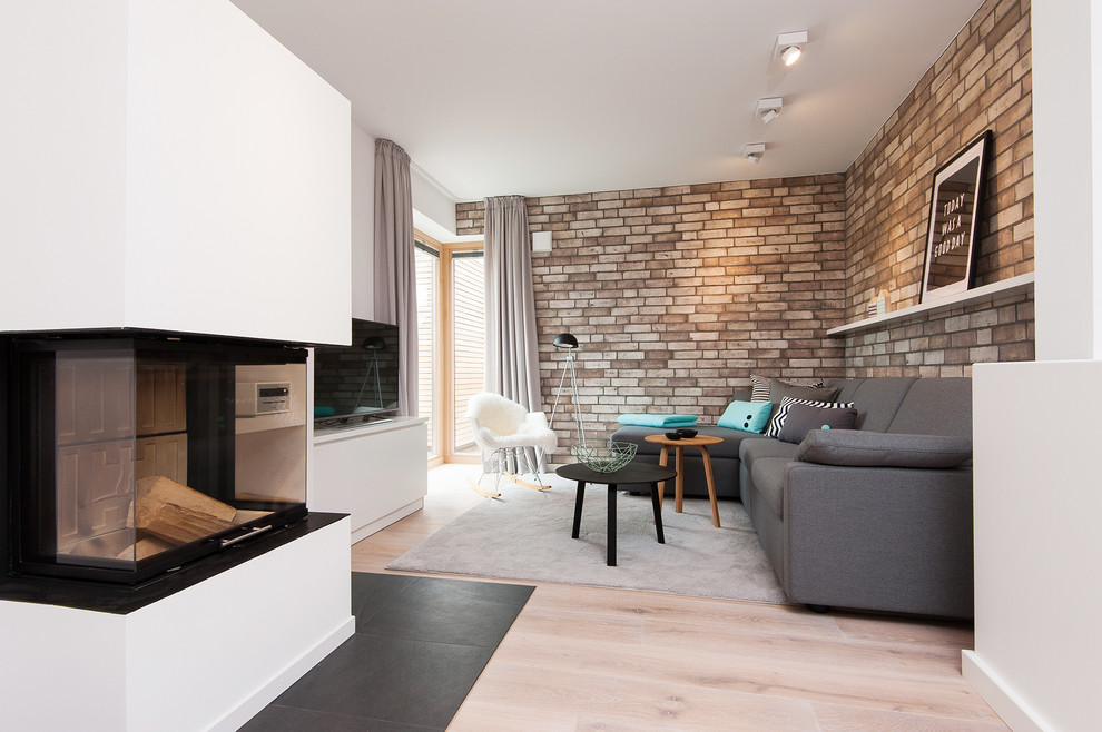 Ejemplo de sala de estar abierta escandinava de tamaño medio con paredes blancas, suelo de madera clara, marco de chimenea de metal, televisor independiente y chimenea de esquina