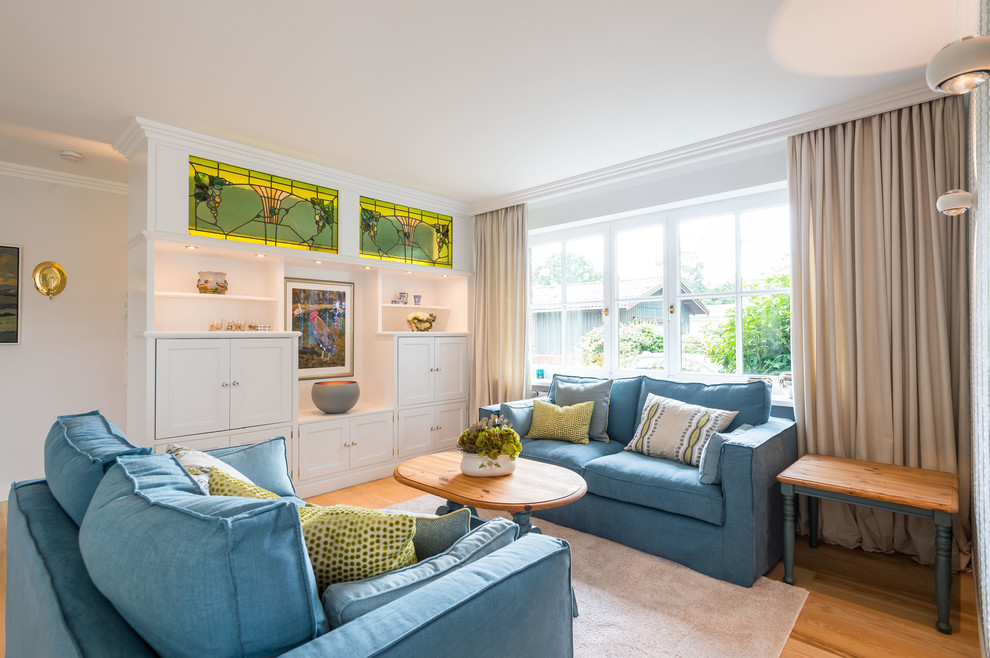 Imagen de sala de estar abierta de estilo de casa de campo de tamaño medio con paredes grises, suelo de madera clara, televisor retractable y suelo beige
