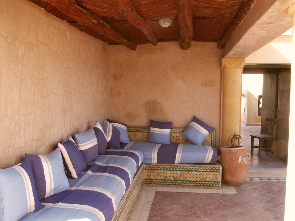 Mediterranes Wohnzimmer mit brauner Wandfarbe und Terrakottaboden in Sonstige