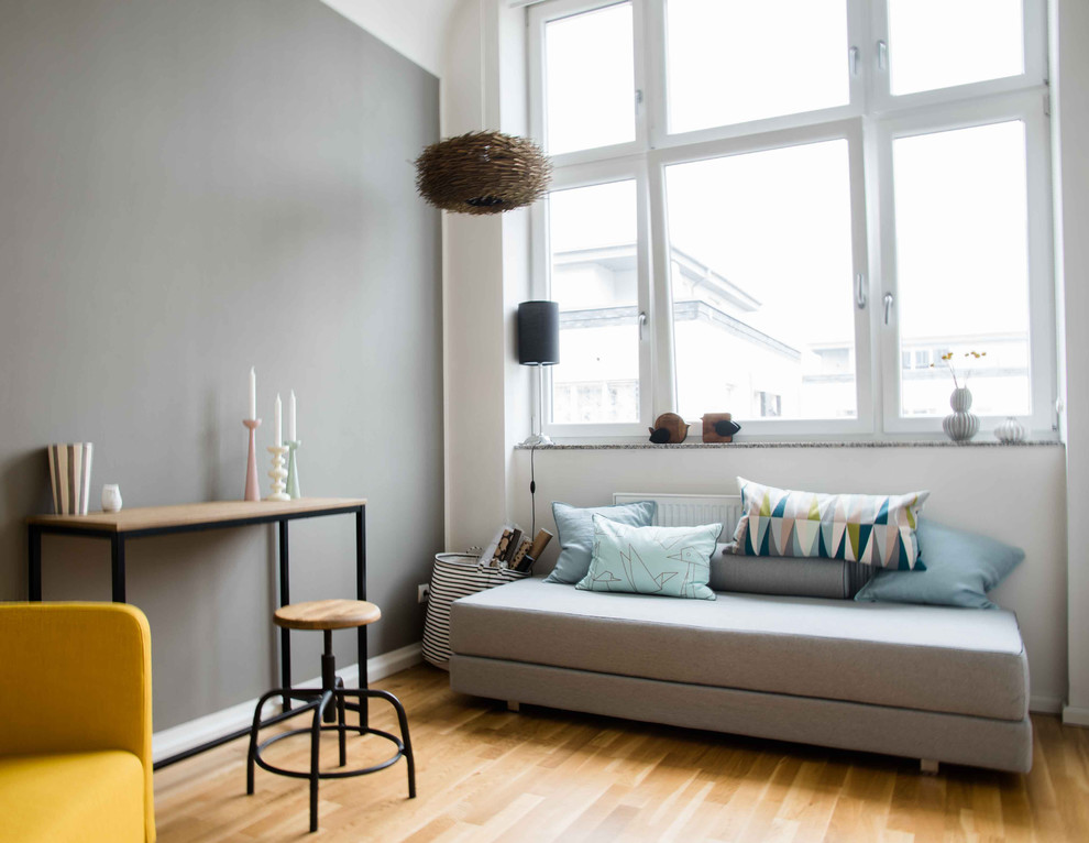 Cette photo montre un petit salon scandinave avec un mur gris et un sol en bois brun.