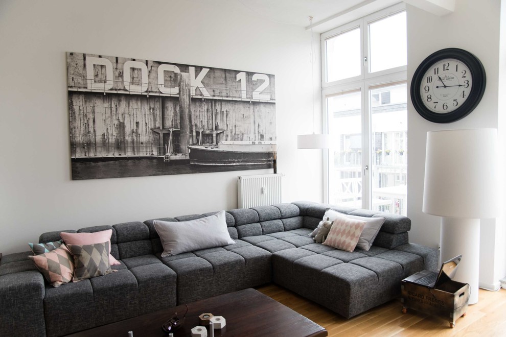 На фото: гостиная комната в скандинавском стиле с белыми стенами и паркетным полом среднего тона с