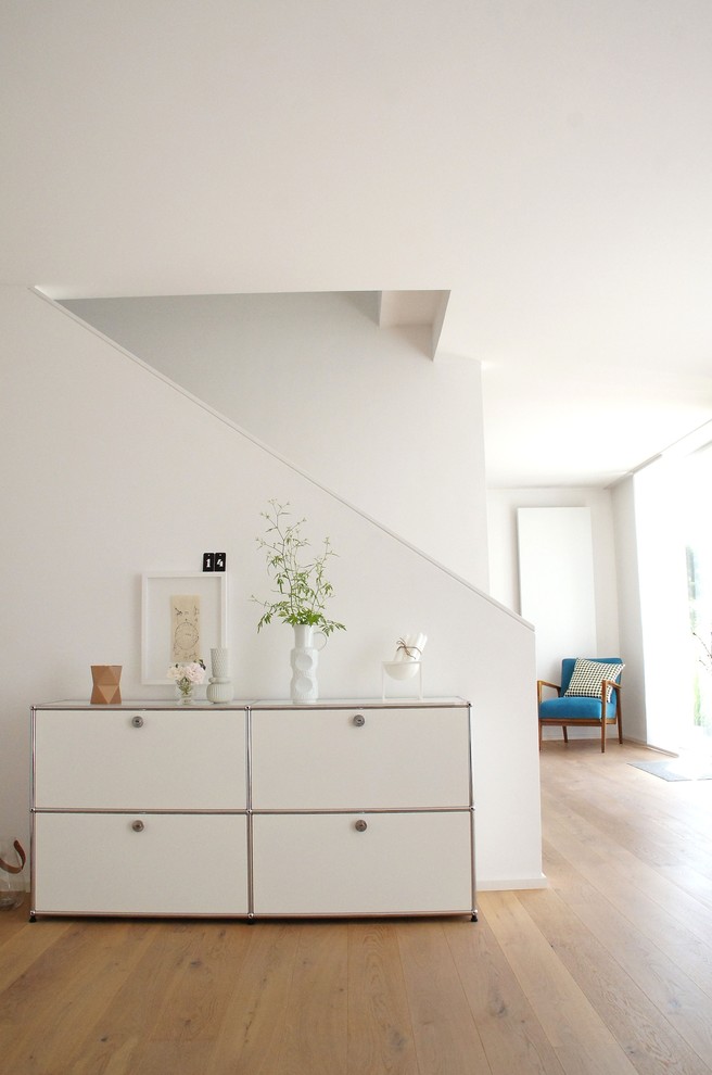 Modelo de sala de estar abierta contemporánea con paredes blancas y suelo de madera en tonos medios