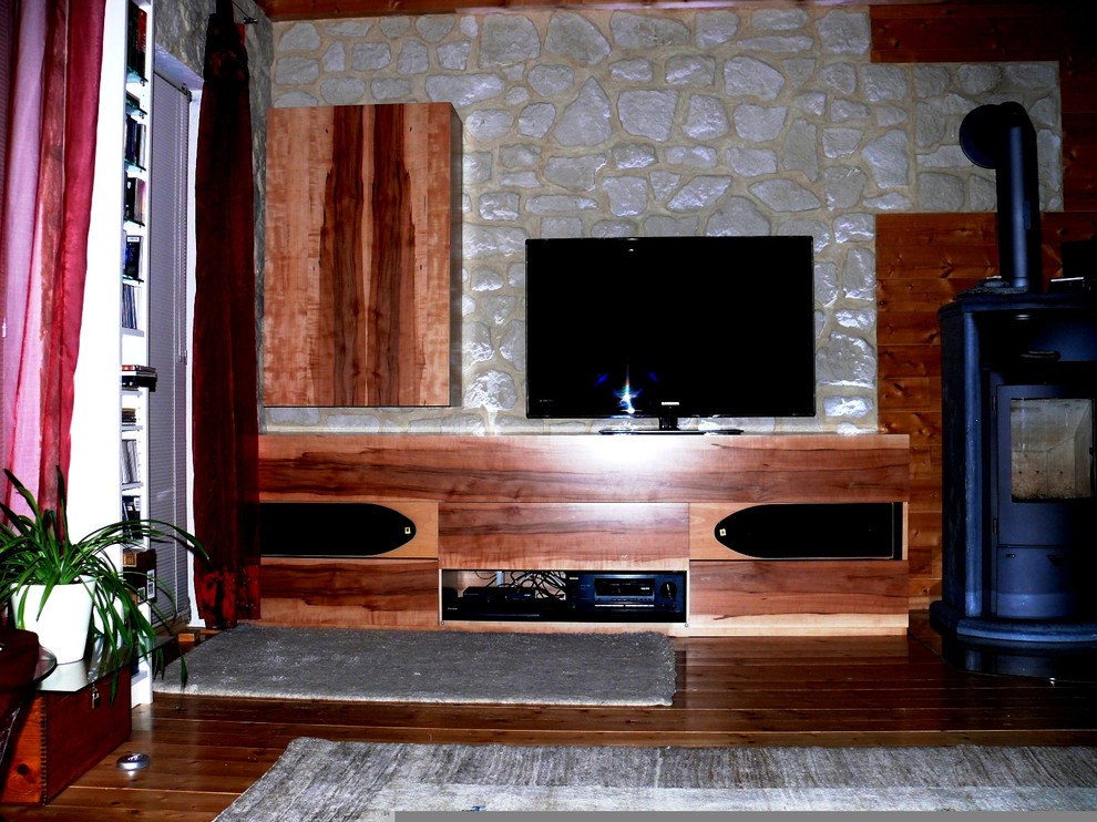 Ejemplo de sala de estar con rincón musical tipo loft contemporánea pequeña con paredes grises, suelo de madera pintada, estufa de leña, marco de chimenea de piedra, pared multimedia y suelo marrón
