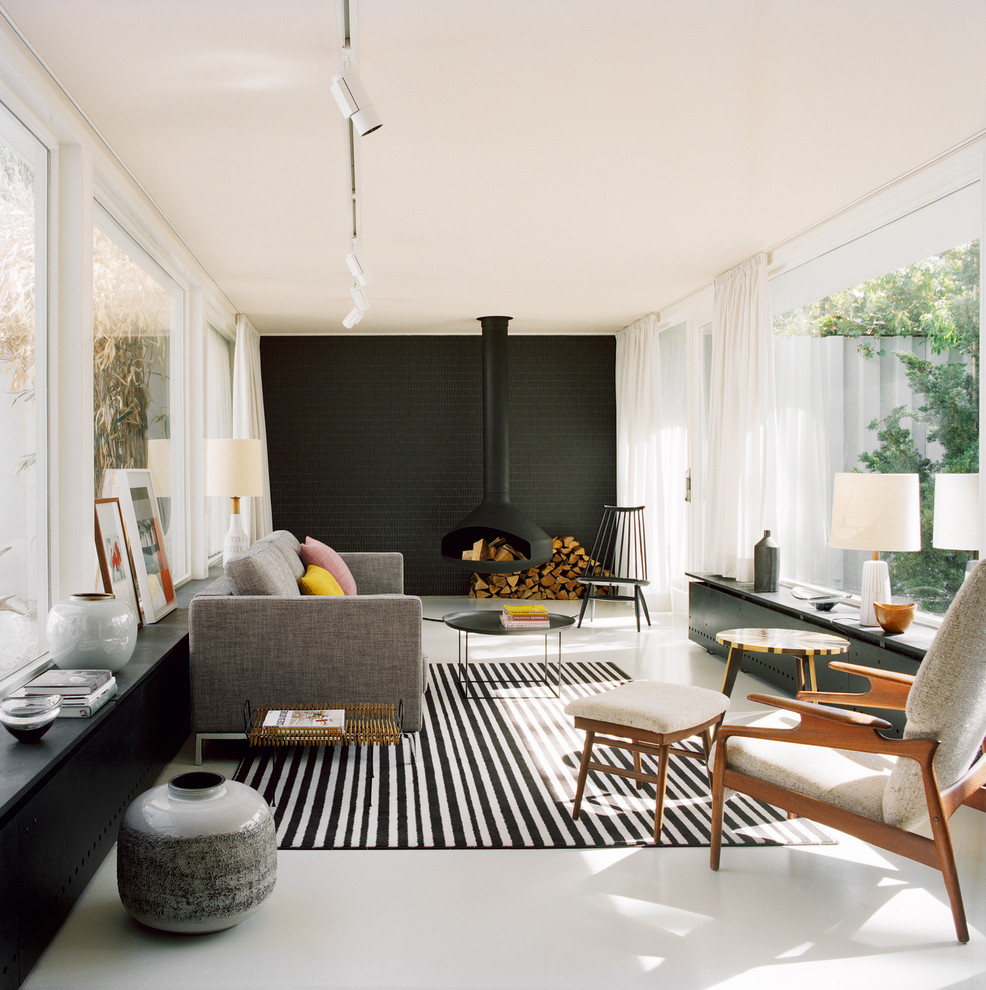 Large scandi enclosed living room in Berlin with black walls, a hanging fireplace and a metal fireplace surround.