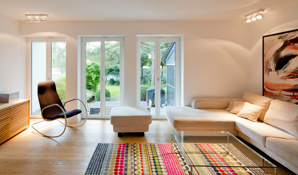 Cette image montre une grande salle de séjour design fermée avec un mur blanc et parquet clair.