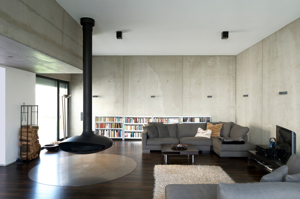 Esempio di un grande soggiorno industriale stile loft con pareti grigie, pavimento in cemento, camino sospeso, cornice del camino in metallo e TV autoportante