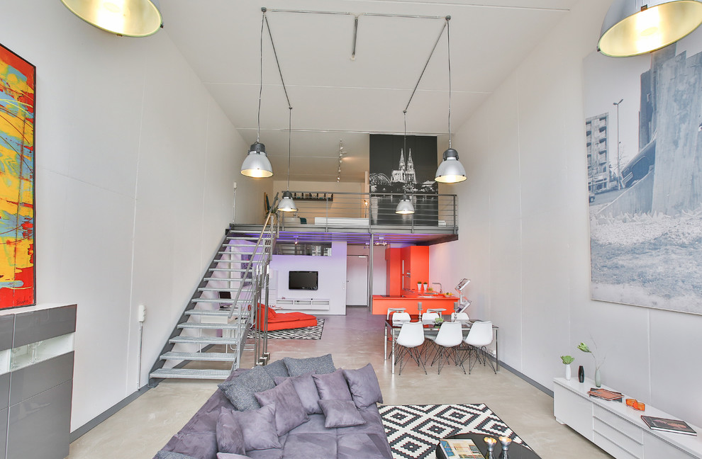 Modelo de salón tipo loft industrial extra grande sin chimenea con paredes blancas, televisor colgado en la pared y suelo beige