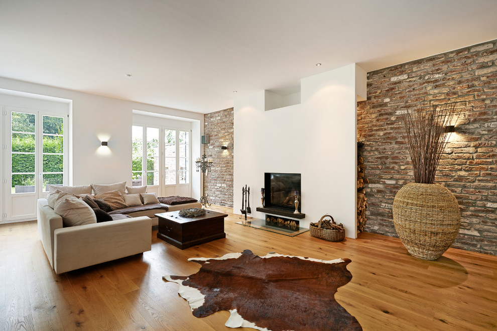 Großes, Offenes, Fernseherloses Modernes Wohnzimmer mit weißer Wandfarbe, braunem Holzboden, Kamin und verputzter Kaminumrandung in Düsseldorf