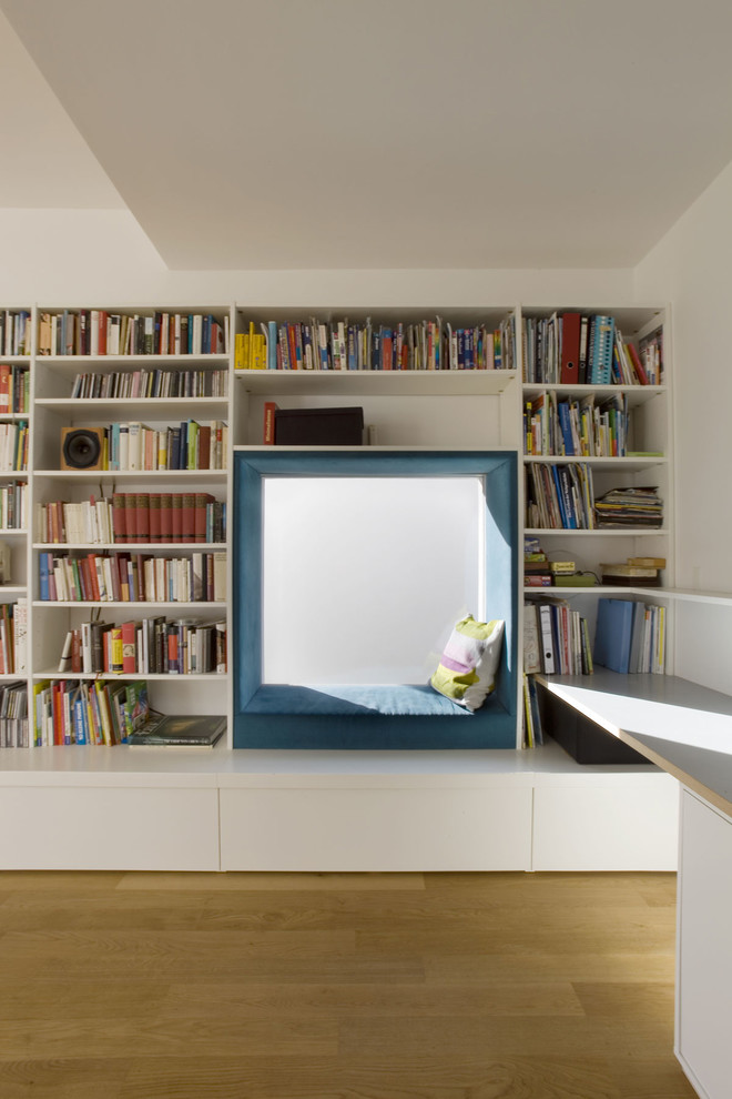 Example of a mid-sized trendy medium tone wood floor family room library design in Berlin with white walls and no fireplace