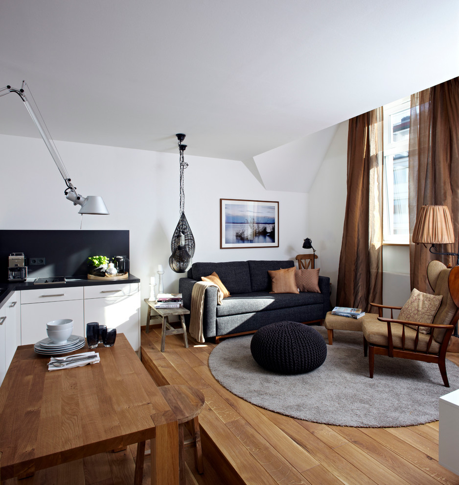 Idée de décoration pour un petit salon design ouvert avec un mur blanc et un sol en bois brun.